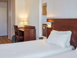 a hotel room with a bed and a desk and a desk at Aparthotel Adagio Access Paris Saint-Denis Pleyel in Saint-Denis