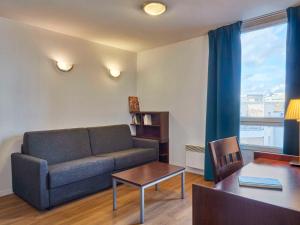 a living room with a couch and a table at Aparthotel Adagio Access Paris Saint-Denis Pleyel in Saint-Denis