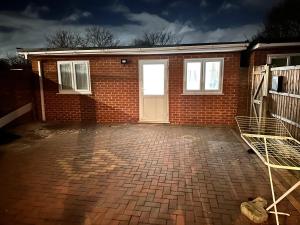 a brick house with a white door and a driveway at One small bed apartment by monishortlets in Dagenham