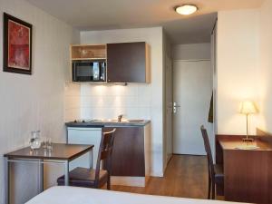 une petite cuisine et une salle à manger avec une table et une salle à manger dans l'établissement Aparthotel Adagio Access Paris Saint-Denis Pleyel, à Saint-Denis