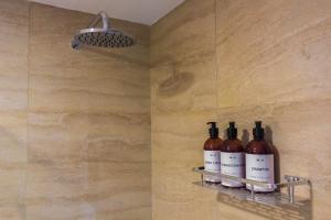 tres botellas de vino sentadas en un estante en una ducha en LA TUA CASA en San Carlos de Bariloche