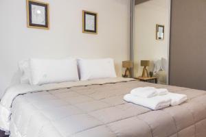 Un dormitorio con una cama blanca con toallas. en LA TUA CASA en San Carlos de Bariloche