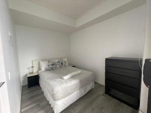 um quarto branco com uma cama e uma cómoda em Entire 2 bedrooms Security Apartment em Riverwood