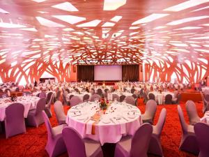 un salón de banquetes con mesas y sillas blancas y una pantalla en Sofitel Abidjan Hotel Ivoire en Abiyán