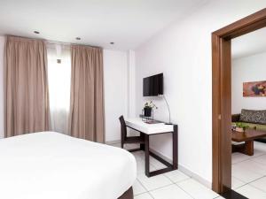 1 dormitorio con 1 cama y escritorio con TV en Ibis Styles Accra Airport en Accra