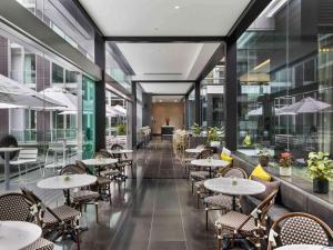 a restaurant with tables and chairs and windows at Sofitel Auckland Viaduct Harbour in Auckland