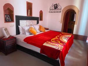 a bedroom with a large bed with a red blanket at Tafsut dades guesthouse stay with locals in Tamellalt
