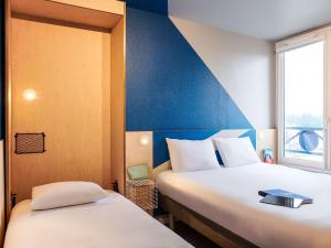 ein Hotelzimmer mit 2 Betten und einem Fenster in der Unterkunft Hôtel Ibis Budget Nantes Ouest Atlantis Couëron in Couëron