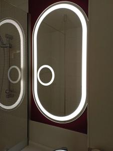 ein Bad mit einem runden Spiegel und einem Fenster in der Unterkunft ibis les Etangs des Moines in Fourmies