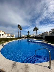 een groot blauw zwembad met palmbomen op de achtergrond bij Sonido del Mar in Gran Alacant