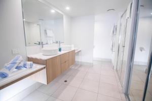 a white bathroom with two sinks and a shower at Club Wyndham Airlie Beach in Airlie Beach