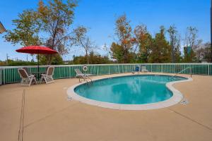 a swimming pool with an umbrella and chairs and a table at Comfort Inn & Suites Santee I-95 in Santee