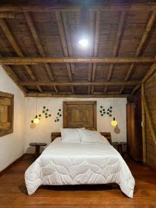 a bedroom with a large white bed with a wooden ceiling at Cabaña Bamboo House in Calarcá