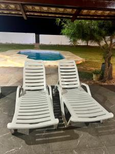 - deux chaises de jardin blanches installées à côté de la piscine dans l'établissement Casa de Praia no Morro Branco, à Beberibe