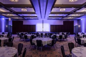 a ballroom with tables and chairs and purple lighting at The Atrium Hotel & Conference Centre Paris CDG Airport, by Penta in Roissy-en-France