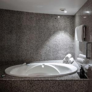 a bathroom with a large white tub in a room at The Atrium Hotel & Conference Centre Paris CDG Airport, by Penta in Roissy-en-France