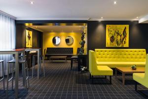 Best Western Hotel Atrium Valence في فالنسيا: مطعم فيه كنب اصفر وطاولات وكراسي