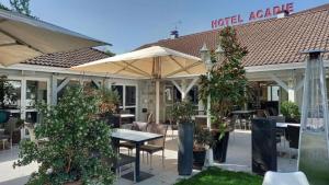 a hotelaria restaurant with tables and trees in front of it at Best Western Hotel Acadie Paris Nord Villepinte in Tremblay-En-France