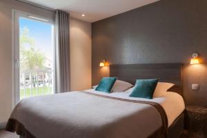 トランブレ・アン・フランスにあるBest Western Hotel Acadie Paris Nord Villepinteのベッドルーム1室(大きなベッド1台、大きな窓付)