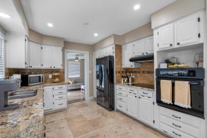 a large kitchen with white cabinets and appliances at Tranquil Paradise 4BR - 2 Miles To Tampa Bucs Stadium in Tampa