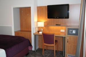 a hotel room with a desk with a bed and a tv at City Hotel Niederrad in Frankfurt