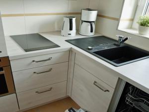 een kleine keuken met een wastafel en een fornuis bij Holiday apartment in Norddeich