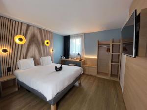 sypialnia z łóżkiem z kotem siedzącym na nim w obiekcie Best Western Bourgoin Jallieu w mieście Bourgoin