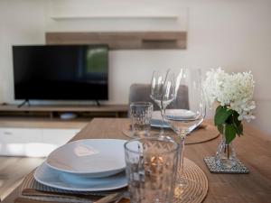 einen Holztisch mit Gläsern und Tellern sowie einen TV in der Unterkunft Green Residence XL in Wildschönau