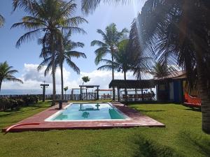 a resort with a swimming pool and palm trees at Pousada Flor de Elisa frente a praia in Caraíva