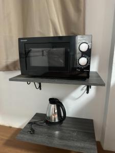 a microwave oven sitting on a shelf with a kettle at Hommie by De-A-Ga in Ban Bang Talat
