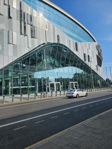 a car driving in front of a glass building at Tottenham Hotspurs Stays at the Gascoigne Suite in London