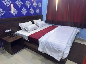1 dormitorio con 1 cama con sábanas y almohadas blancas en OYO The Mount View en Jamshedpur
