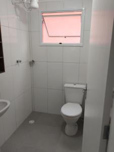 uma casa de banho com um WC e uma janela em Cantinho do descanso em Bertioga