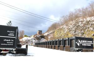 Pociąg stoi obok pokrytego śniegiem wzgórza. w obiekcie RJ HOTELS OTARU w mieście Otaru