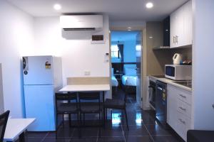 a kitchen with a white refrigerator and a table and chairs at Best Western Plus Buckingham International in Moorabbin