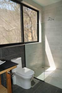 e bagno con servizi igienici, doccia e finestra. di Loft hermoso entre el bosque, vista al Lago. a Valle de Bravo