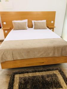 1 dormitorio con 1 cama grande y cabecero de madera en AMU- Apartamentos Mistérios da Urzelina en Urzelina