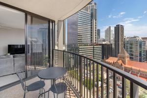 balcón con mesa, sillas y vistas a la ciudad en Queen St Residence en Brisbane