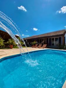 una piscina con una fuente de agua frente a una casa en Noah Hostel & Chale, en São Miguel do Gostoso