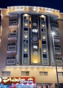Un grand bâtiment avec des lumières sur son côté dans l'établissement ليله ود للشقق المخدومة - Laylt wed, à Djeddah