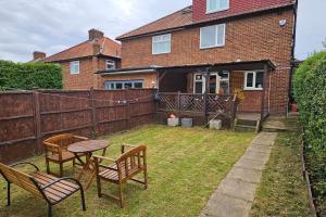 a backyard with two chairs and a table and a fence at Cozy & Elegant 4 Bedroom Home Near Wembley in The Hyde