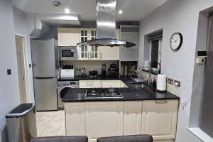 a kitchen with a sink and a stove top oven at Cozy & Elegant 4 Bedroom Home Near Wembley in The Hyde