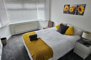 a bedroom with a bed with a yellow blanket on it at Cozy & Elegant 4 Bedroom Home Near Wembley in The Hyde