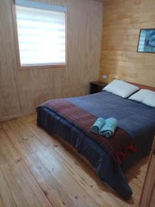 1 dormitorio con 1 cama con manta azul y ventana en Cabaña Loremar Pastahue, en Castro