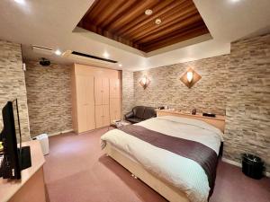 武雄市SKY Lmine Takeo LOVEHOTEL的一间带大床和石墙的卧室