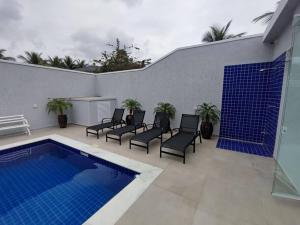 a patio with chairs and a swimming pool at Belissima casa Jardim Acapulco in Guarujá