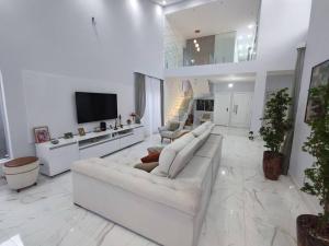 sala de estar blanca con sofá blanco y TV en Belissima casa Jardim Acapulco, en Guarujá