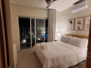 1 dormitorio con cama blanca y ventana en Escapada en Boca chica, en Boca Chica