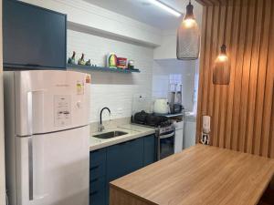 a kitchen with a white refrigerator and blue cabinets at Apto em Bertioga , pé na areia in Bertioga