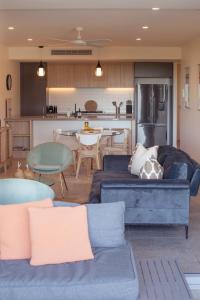 a living room with two blue couches and a kitchen at The Beach Oasis ~ Dune in Kingscliff